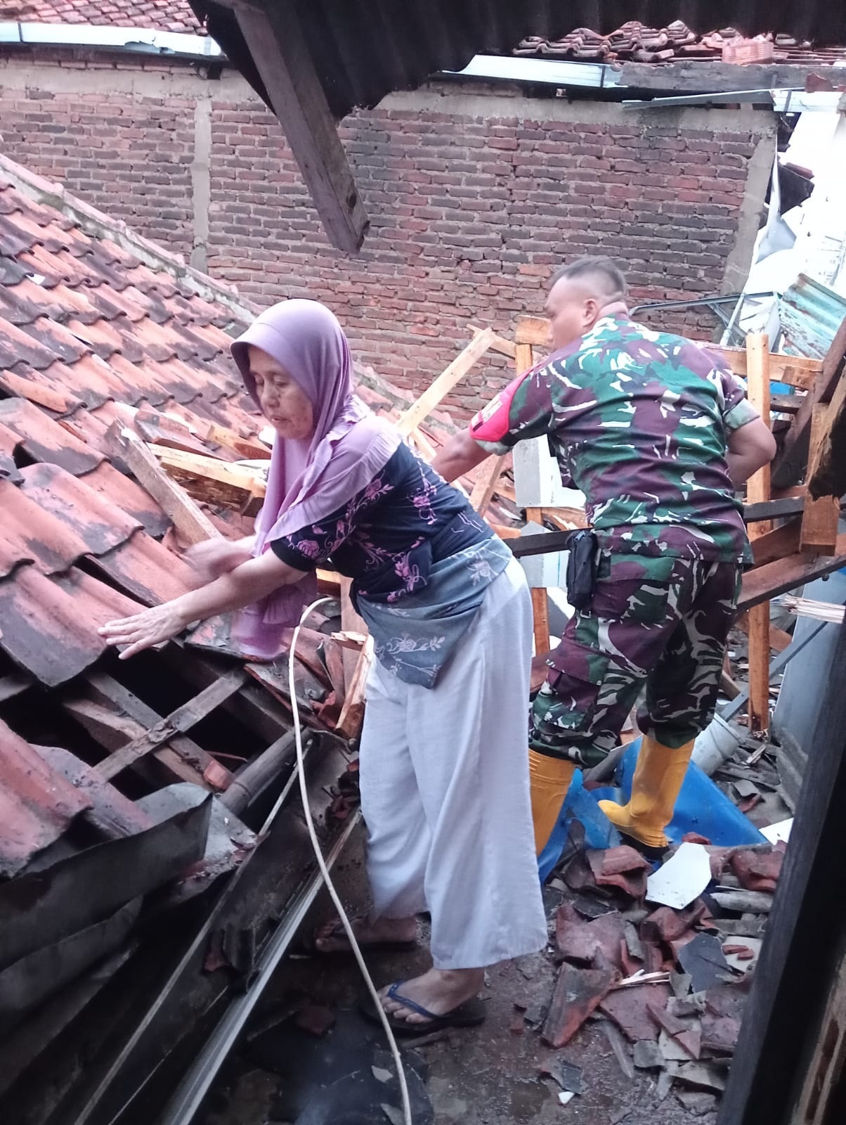 Sertu Adeng Kurnia,saat epakuasi puing -puing matrial bersama warga